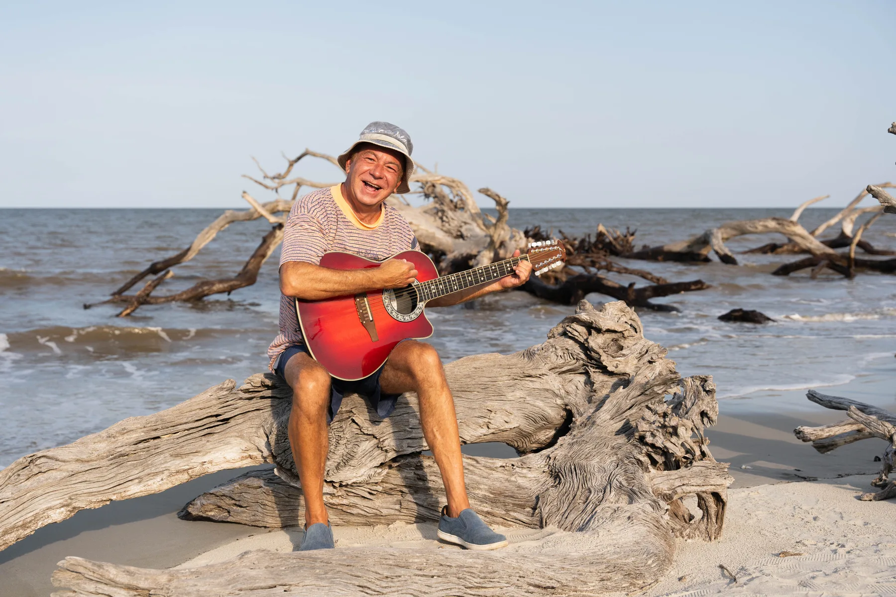 Dan Random playing guitar beside the ocean